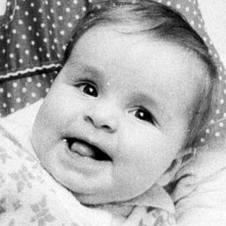 A woman plays with a smiling baby indoors.