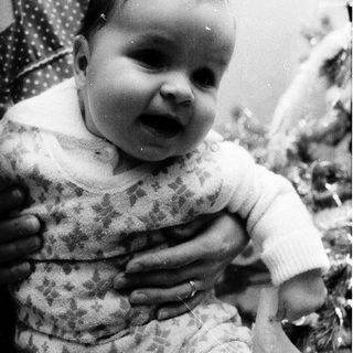 Baby in vintage outfit, smiling indoors.