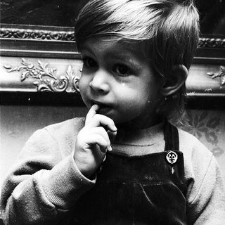 Young child biting finger in indoor setting.