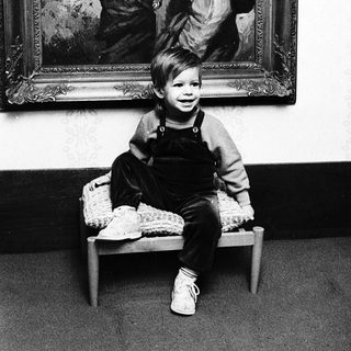 Young child sitting in front of vintage painting.