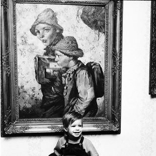 Young child sitting in front of vintage painting.