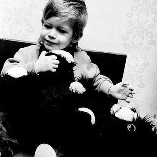 Young child holding stuffed animal indoors.
