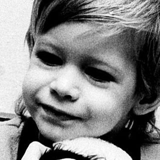 Young child holding stuffed animal indoors.
