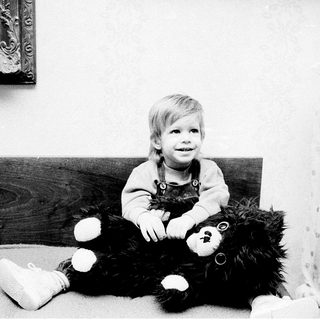 Young child sitting with large teddy bear.
