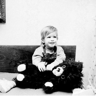 Young child sitting with large teddy bear.
