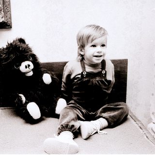 Young child sitting with black teddy bear.