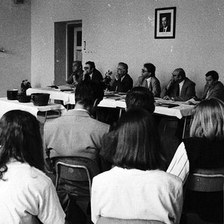 Formal meeting or conference with seated attendees and panelists.