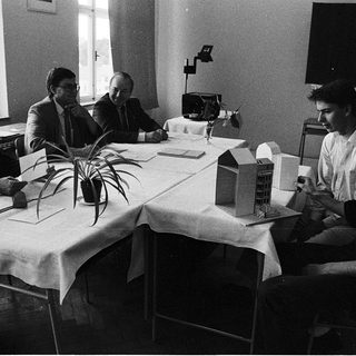 Business meeting with architectural models on table.