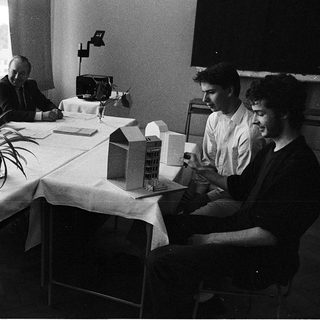 Business meeting with architectural models on table.