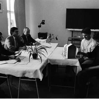 Four men in meeting discussing architectural model.