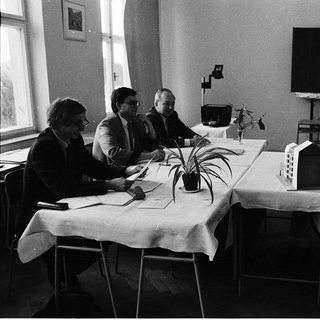 Four men in meeting discussing architectural model.