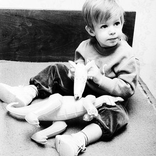 Young child sitting with stuffed animal.