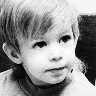 Young child sitting with stuffed animal.