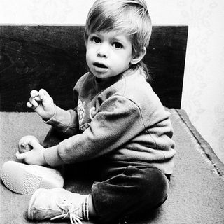 Young child sitting on floor, looking surprised.