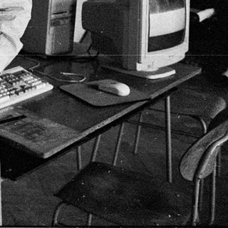 Young man in office using vintage computer equipment.