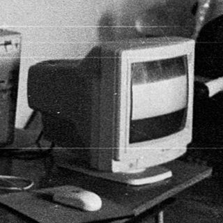 Young man in office using vintage computer equipment.