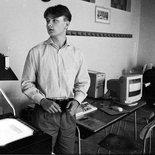 Young man in office using vintage computer equipment.