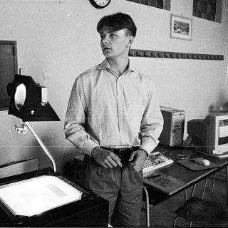 Young man in office using vintage computer equipment.