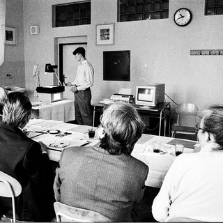 Classroom lecture with vintage computer demonstration.