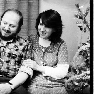 Family portrait with parents and baby near Christmas tree.