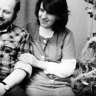 Family portrait with parents and baby near Christmas tree.