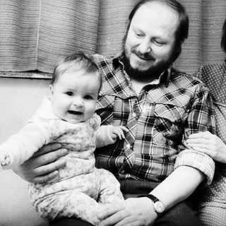 Family portrait with parents and baby near Christmas tree.