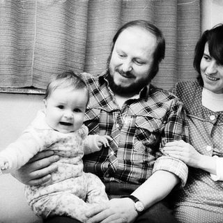 Family portrait with parents and baby near Christmas tree.