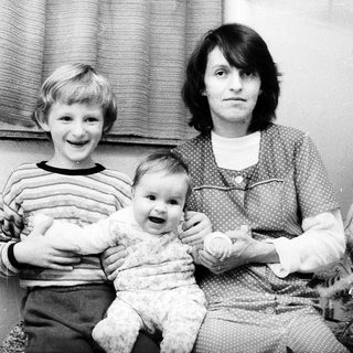 Family portrait with mother, toddler, and young boy.