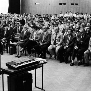 Formal conference or lecture with seated audience listening.