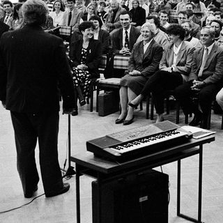 Formal conference or lecture with seated audience listening.