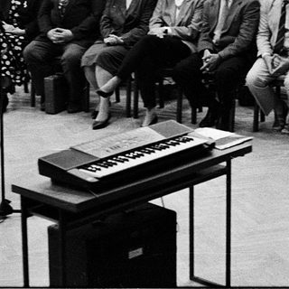 Large audience listens to a speaker at a formal event.
