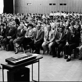 Large audience listens to a speaker at a formal event.