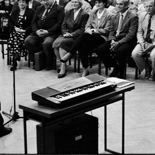 Large audience listens to a speaker at a formal event.