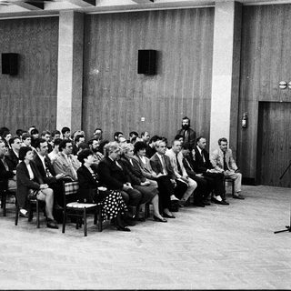 Formal meeting or conference with speaker addressing seated audience.
