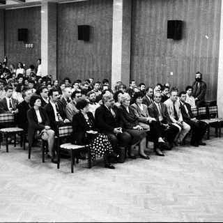 Formal indoor lecture or meeting with speaker addressing audience.
