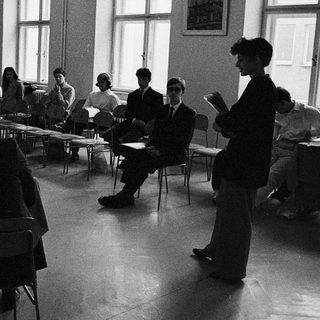 Classroom discussion or lecture with students seated at tables.