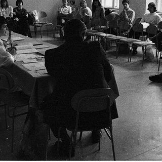 Classroom discussion or lecture with students seated at tables.