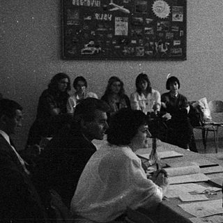 Classroom discussion or lecture with students seated at tables.