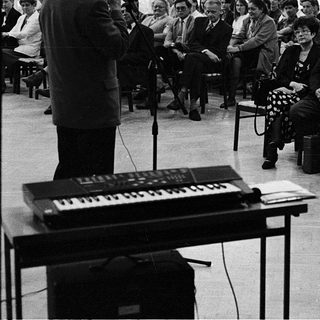 Man speaking to audience at indoor lecture or meeting.