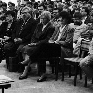 Man speaking to audience at indoor lecture or meeting.