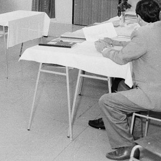 Classroom seminar or meeting with participants seated and a speaker presenting.
