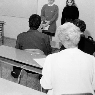 Classroom scene with teacher and students in 1970s-style schoolroom.
