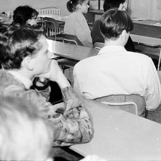 Classroom scene with teacher and students in 1970s-style schoolroom.