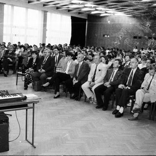 Large indoor audience listening to a lecture or performance.