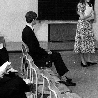 Classroom lecture with woman speaking at blackboard.
