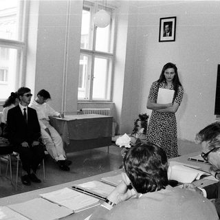 Classroom meeting with students and instructors discussing documents.