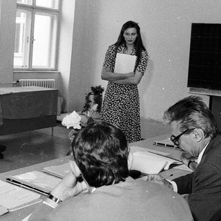 Classroom meeting with students and instructors discussing documents.