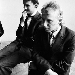 Two men in suits sitting thoughtfully indoors.
