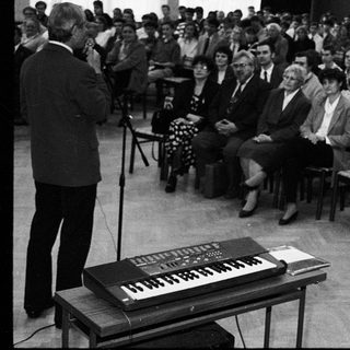 A formal lecture or conference with speaker and seated audience.