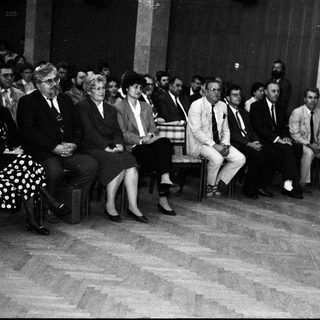Formal indoor gathering with speaker addressing seated audience.